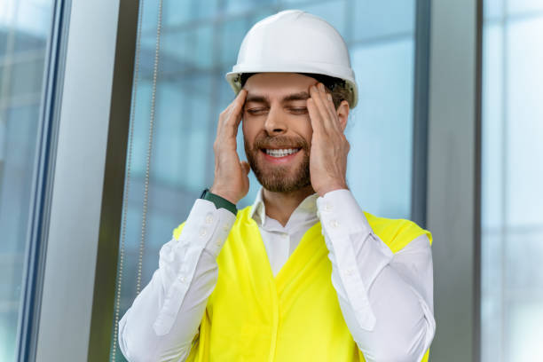 istock Young bearded caucasian man in protective cap suffering from a headache 2193913473