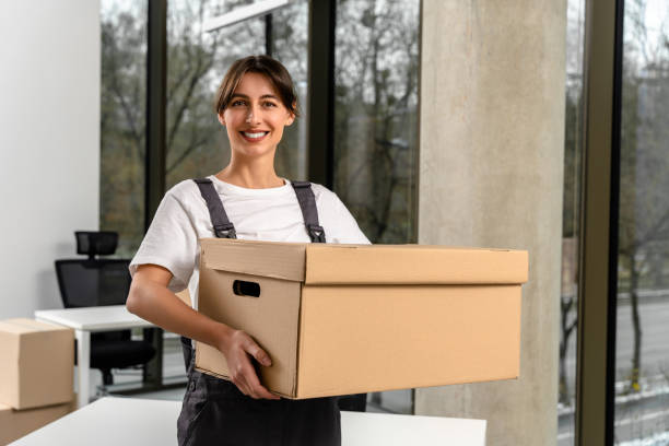 istock Smiling female dark-haired young packaging service worker holding a big parcel 2193913662