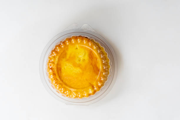 A freshly baked round butter bun enclosed in clear plastic packaging, displayed on a white background. perfect for bakery promotions, and food advertising.