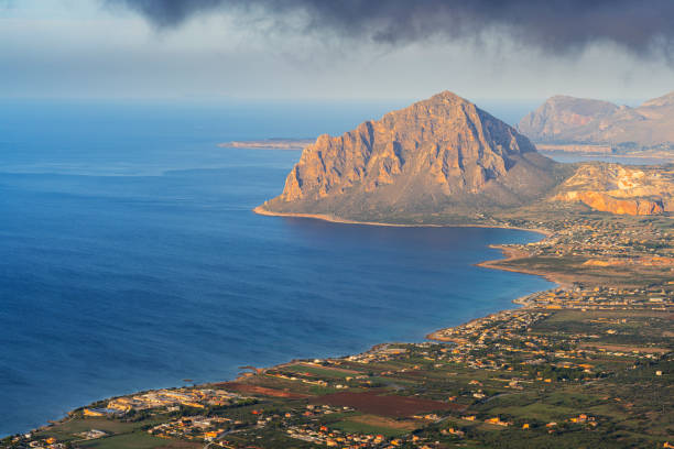 Elevated view of dramatic rocky coastline with mount Cofano in the distant at sunset, Erice, Trapani, Sicily, Mediterranean sea, Italy