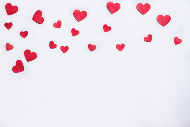 Red heart shaped confetti forming a frame for Valentine's day card or wedding invitation. Copy space