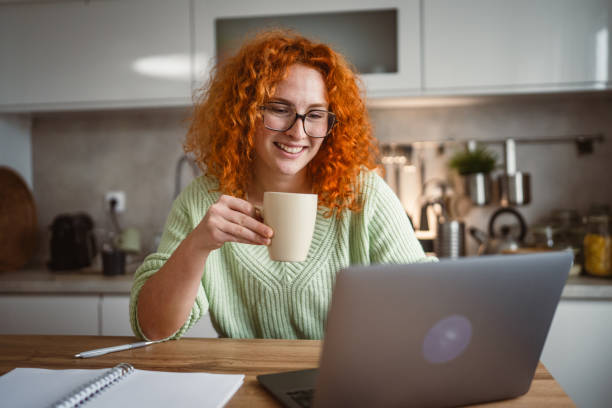 istock adult woman with coffee mug work on laptop computer at kitchen happy 2193925036
