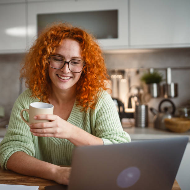 istock adult woman with coffee mug work on laptop computer at kitchen happy 2193925207