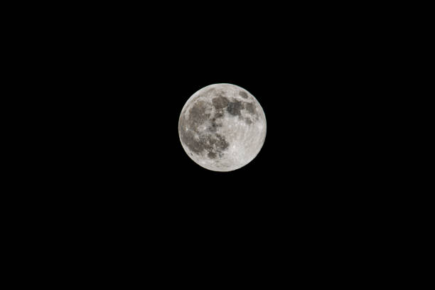 Image of a bright moon rising in the dark sky