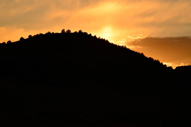 istock Setting Sun Against Silhouetted Hill Against Dramatic Dusk Sky 2193926362