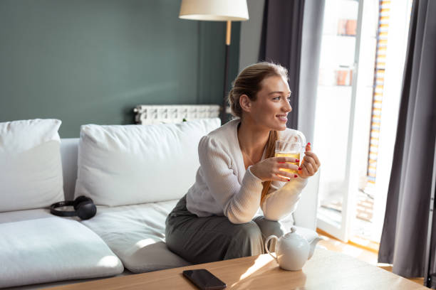 istock Young woman enjoying a warm cup of tea while relaxing on the sofa 2193927220