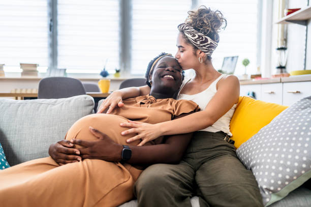 istock Pregnant lesbian couple relaxing on sofa 2193930205