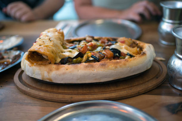 Turkish vegetable stew in flatbread, with eggplant, carrot, onions. Incidental people at table.