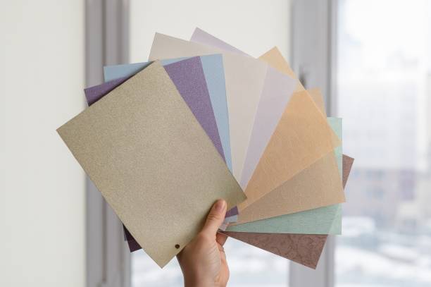 istock Woman holding fabric samples of roller blinds against window background. 2193932102