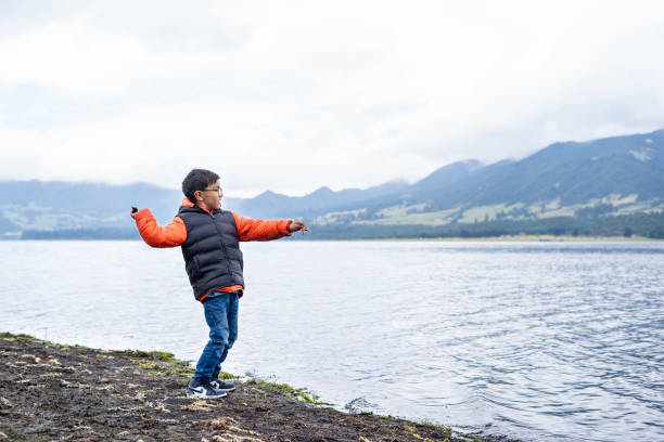 istock Latin boy throwing stones into a lagoon. 2193936313