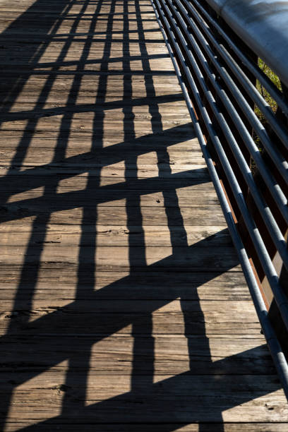 Light and shadows creating a geometric pattern on a wooden bridge deck at the Buffalo Bayou Park, Houston, Texas