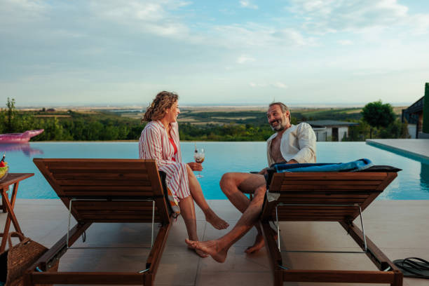 istock Couple enjoying relaxing drinks by infinity pool overlooking scenic countryside 2193940263