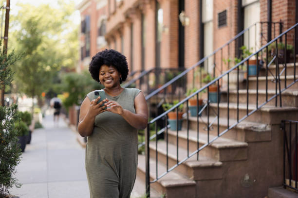 istock Woman Using Smartphone While Walking in an Urban Neighborhood 2193940703