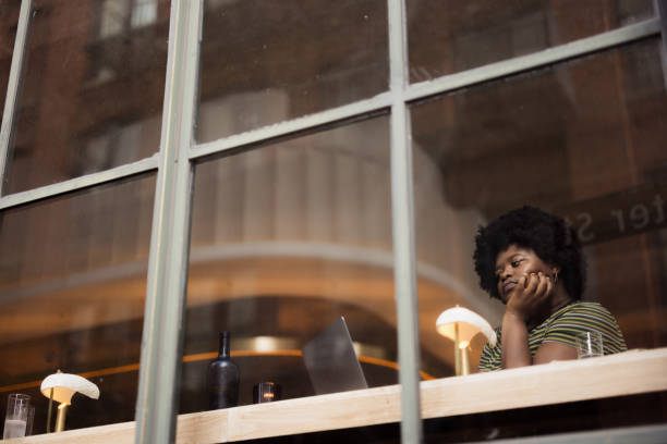 Reflective Moment by Window with Laptop at a Cozy Cafe