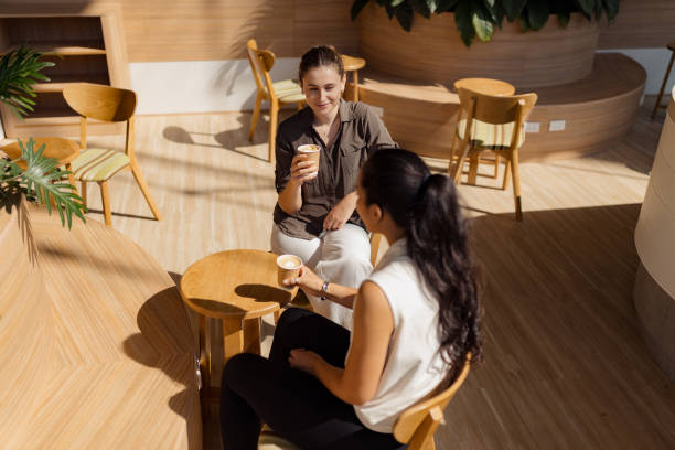 istock Two Women Enjoying Coffee in a Modern Cafe with Natural Light 2193940836