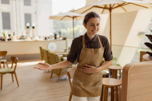 istock Smiling Waitress Welcoming Guests at a Modern Indoor Cafe 2193940859