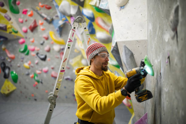 istock A worker mounting climbing grips on a newly constructed climbing structure. 2193941172