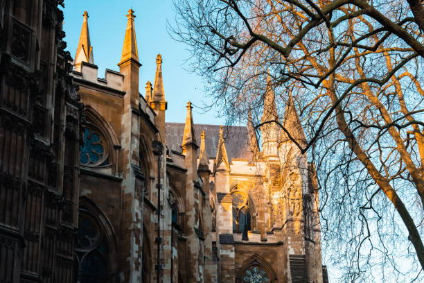Westminster abbey glows in the warm light of the setting sun, its intricate gothic architecture highlighted against the clear blue sky