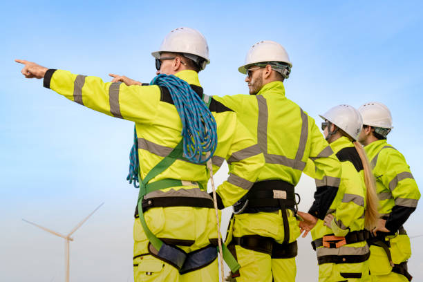 istock engineers in high visibility gear and hard hats work at a wind farm, pointing and discussing wind energy operations. The wind turbines in the background emphasize teamwork renewable energy sector. 2193947609