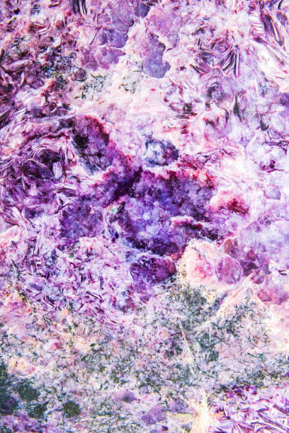 Verticla photo texture of charoite with a coarsely banded structure. Polished sample. Abstract natural mineral background