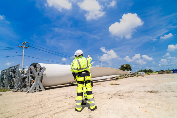 istock Engineers in high visibility gear assess a large wind turbine blade at a construction site under a bright blue sky, representing the implementation of renewable energy technology for sustainable. 2193949472