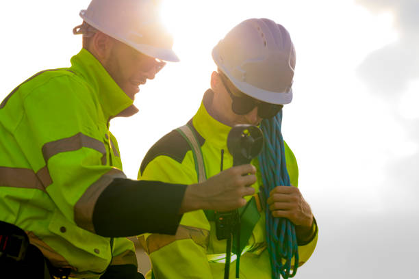 istock Two engineers wearing high visibility safety jackets and helmets measure wind speed with an anemometer and analyze data on a tablet at a renewable energy site. The cloudy sky adds depth to the scene. 2193949517