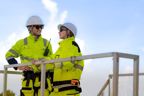 istock Two engineers in high visibility gear and hard hats observe a wind turbine and communicate via radio at a wind energy site. The image highlights teamwork, safety, and renewable energy production. 2193950112