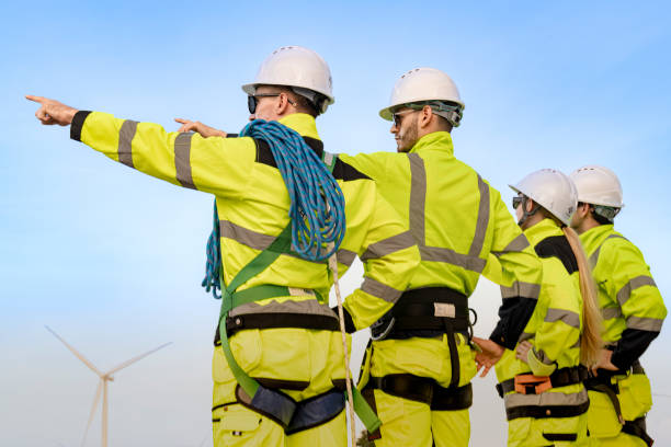 istock engineers in high visibility gear and hard hats work at a wind farm, pointing and discussing wind energy operations. The wind turbines in the background emphasize teamwork renewable energy sector. 2193950192