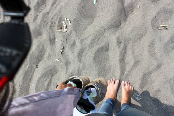 A pair of feet buried in the warm sand of a tropical beach, with the ocean waves crashing in the background. The image evokes a sense of relaxation and tranquility.