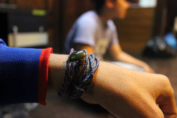 Beetle showcased on a person's palm, shot with a shallow depth of field. The background hosts blurred figures, suggesting an indoor communal setting highlighting nature's intricate beauty.