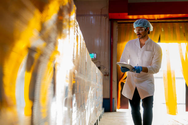 Technician inspecting stacked products in a brightly lit warehouse Focus on quality control logistics and industrial efficiency in modern manufacturing settings.