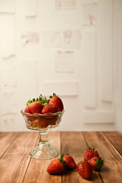 Fresh strawberries in a glass bowl on a wooden surface with a r in United States, Florida, Inverness