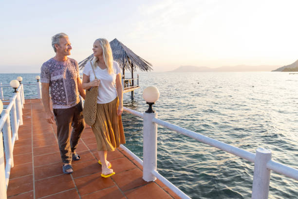 istock Mature couple walk along empty pier at sunrise 2193965345