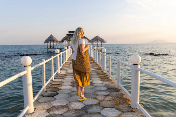 Mature woman walks along empty pier at sunrise, Phu Quoc