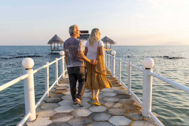 istock Mature couple walk along empty pier at sunrise 2193965433