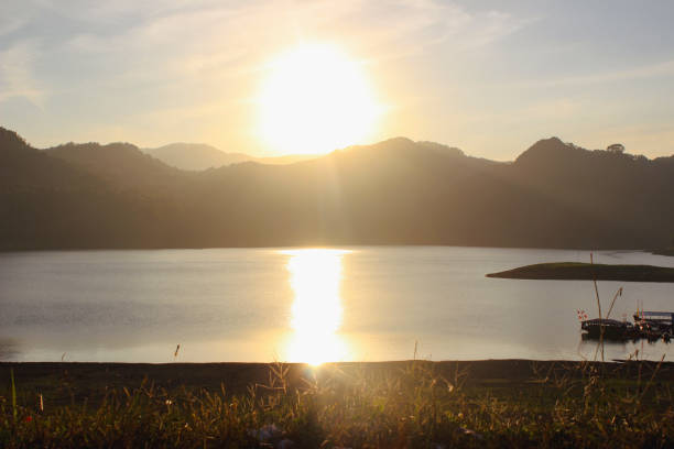 Scenic view of a small mountain pond surrounded by golden grass under the warm glow of sunset.