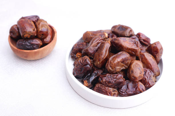 istock Sweet Dates in Bowls: A Close-Up View of Dried Dates on White Surface 2193972563