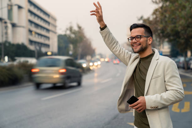 istock Stylish Business Commuter Raising Hand For Cab During Evening Rush 2193977934