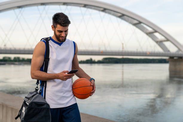 istock Young Athletic Basketball Player Checking Smartphone Before Practice Near Bridge 2193978151