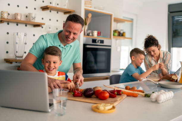 istock Smiling Father and Sons Learning Cooking Skills in Bright Home Kitchen 2193979110
