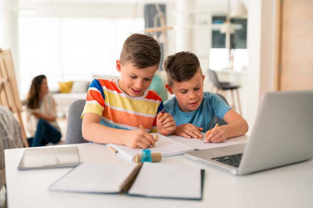 istock Focused Elementary Age Brothers Studying Together With Laptop And Notebooks 2193979244