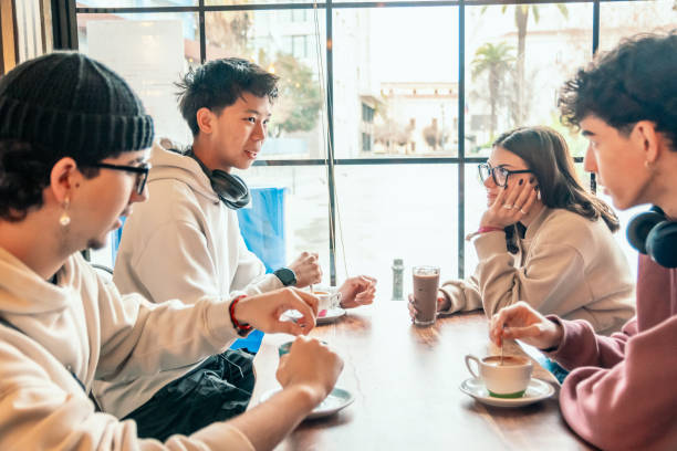 istock Four diverse young students are sitting at a table in a cafe, enjoying coffee and engaging in lively conversation, demonstrating the joys of friendship and shared moments 2193981746