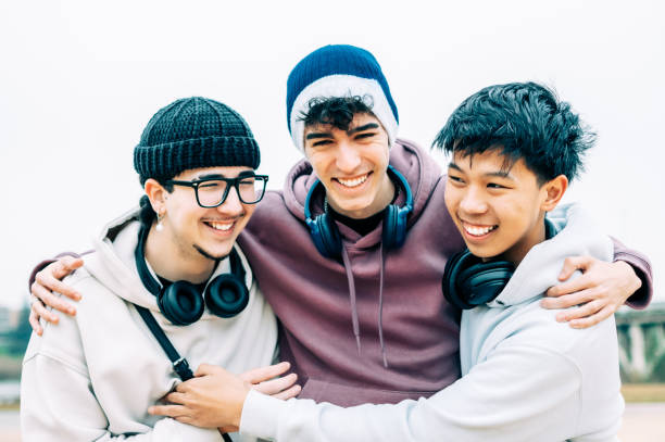 istock Multicultural male students hugging, sharing laughter and camaraderie with headphones draped around necks 2193981804
