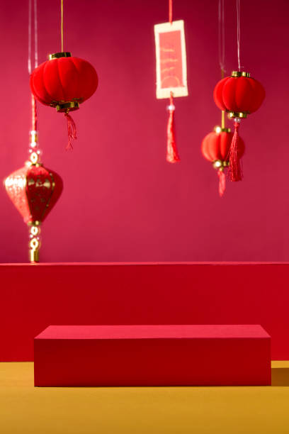 istock A classic idea for the New Year. A product is displayed on empty red cylindrical pedestals, standing on a golden surface in front of a crimson backdrop. Adorned with calligraphy and Chinese lanterns. 2193983782