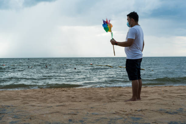 Action shot of young boy jumping with yellow bucket of water on beach during summer holiday, captured with high shutter speed