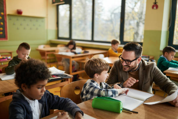 istock Happy professor talking to schoolboy on a class at school. 2193984540
