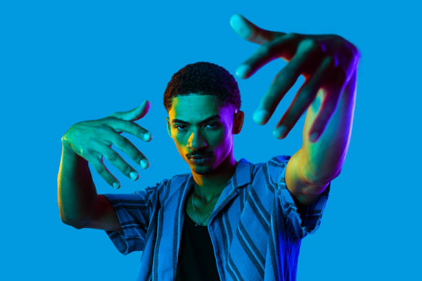 African man young portrait in studio on colorful background - Cool black young male with stylish attire posing , creative colored lighting