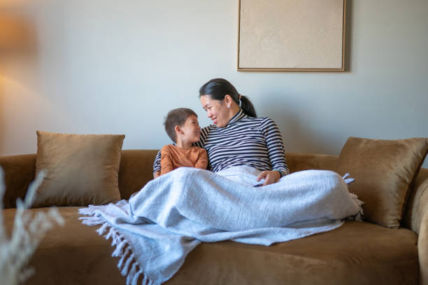 istock Mother and son share loving gaze on brown comfortable sofa. 2193987351