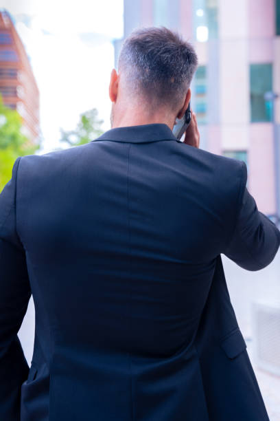 istock Rear view Businessman Talking on Smartphone Outdoors in Urban Setting Vertical 2193989055