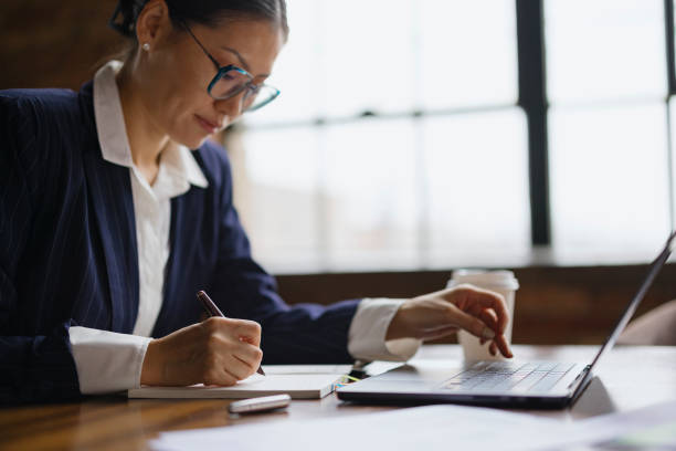 istock Asian businesswoman taking notes while working on laptop in the office. 2193991965